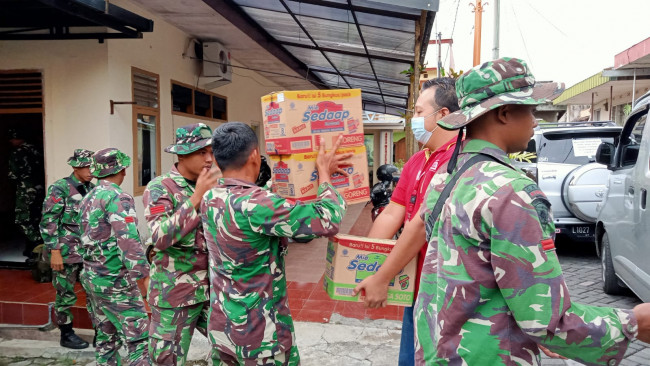 Pegawai Alfamart dibantu oleh jajaran anggota TNI untuk memindahkan barang bantuan dari Alfamart.