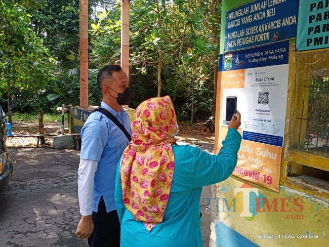 Salah satu pengunjung yang sedang memindai QR Code melalui aplikasi peduli lindungi.(Foto: Istimewa).