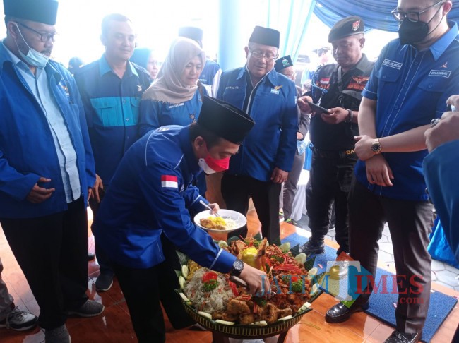 Ketua DPC Partai Demokrat Kabupaten Malang, Ghufron Marzuqi saat memotong tumpeng (foto: Hendra Saputra/JatimTIMES) 