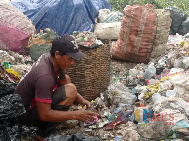 Harianto saat memilah sampah di TPA Supit Urang (foto: Hendra Saputra/JatimTIMES)