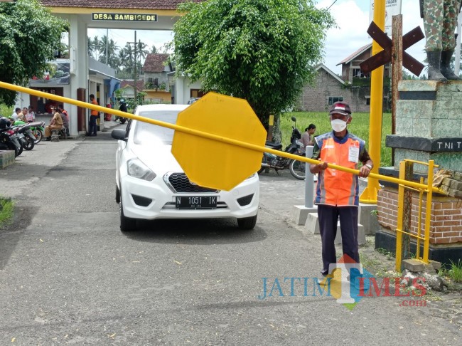 Agus Suyitno saat menutup perlintasan kereta api (foto: Hendra Saputra/JatimTIMES) 