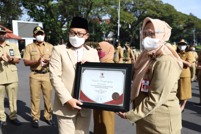 Wali Kota Malang Sutiaji menyerahkan penghargaan kepada Kepala Dispendukcapil Kota Malang Eny Hari Sutiarni.