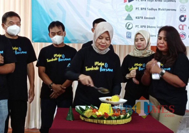 Pemotongan tumpeng yang dilakukan oleh Ketua BPR Group Pitu+ (foto: Hendra Saputra/JatimTIMES)