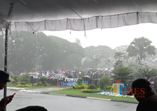 Suasana Aremania yang bertahan dengan hujan-hujan (foto: Hendra Saputra/JatimTIMES) 