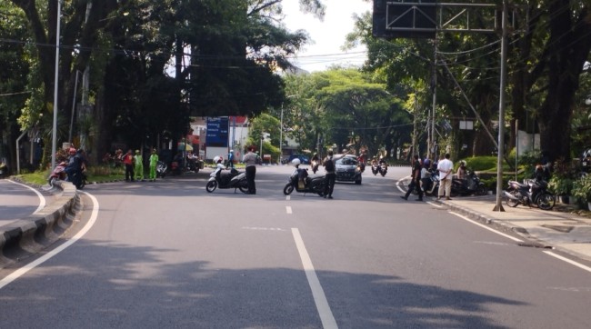 Polisi yang membantu masyarakat untuk menuju jalan alternatif (foto: Hendra Saputra/JatimTIMES)