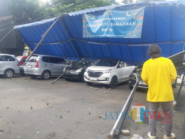 Warga saat menaikkan kembali tenda pasar takjil yang roboh (foto: Hendra Saputra/JatimTIMES)