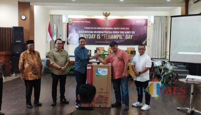 Salah satu buruh yang memperoleh doorprize dan diberikan langsung oleh Pj Wali Kota Malang Wahyu Hidayat (foto: Hendra Saputra/JatimTIMES)