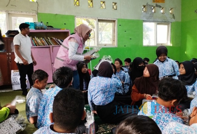 Srikandi PLN UP3 Malang membagikan buku kepada siswa-siswi SDN Kauman 2 Kota Malang (foto: Hendra Saputra/JatimTIMES)