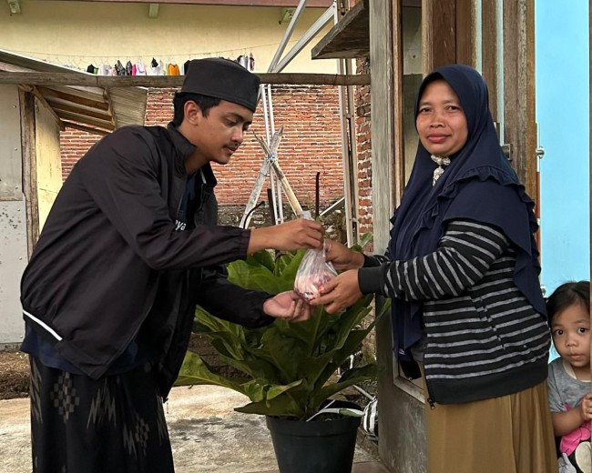 Salah satu santri berbagi daging kurban ke warga sekitar. (Foto: istimewa)