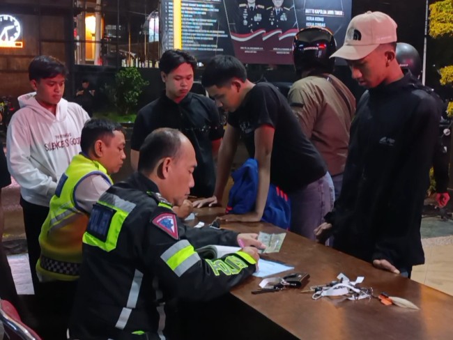 Polisi saat melakukan penilangan pada pelaku aksi balap liar (foto: Hendra Saputra/JatimTIMES) 