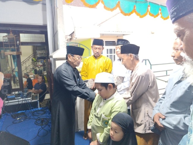 Tri Wediyanto (jubah hitam) secara simbolis saat memberikan santunan (foto: Hendra Saputra/JatimTIMES) 