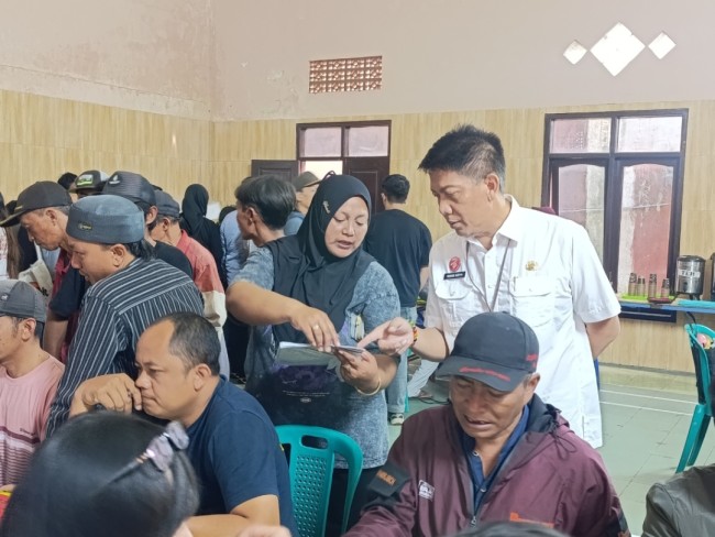 Kepala Bapenda Kabupaten Malang, Made Arya Wedhantara (baju putih) saat membantu warga yang akan bayar pajak di Desa Pujon Lor (foto: Hendra Saputra/JatimTIMES) 