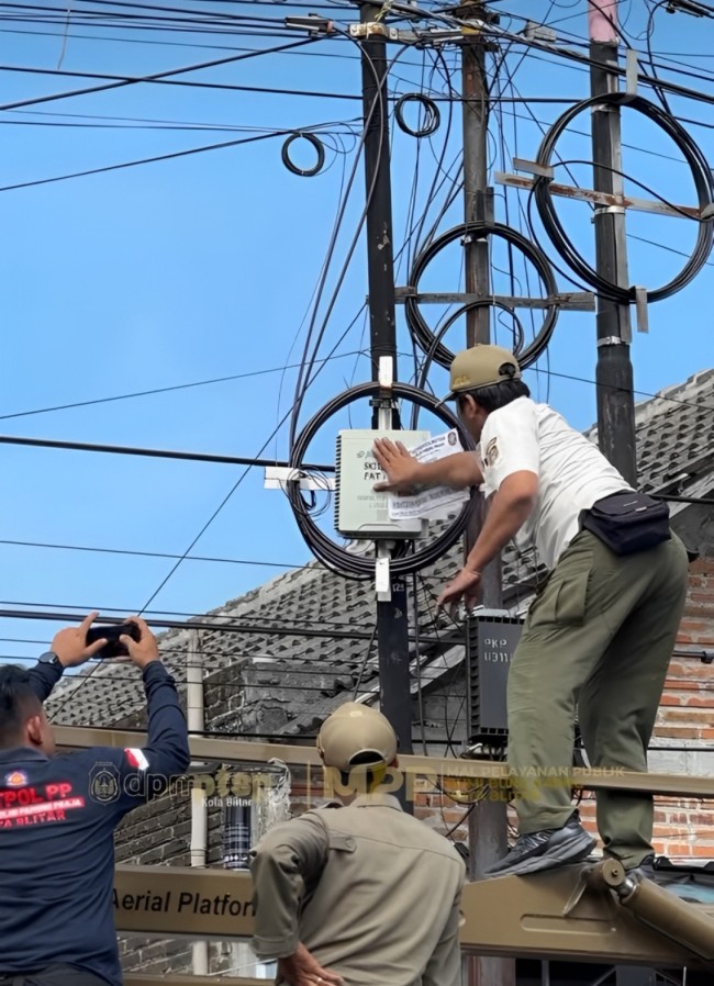 Petugas Satpol PP Kota Blitar menyegel jaringan kabel fiber optik ilegal di salah satu titik fasilitas umum, Kamis (17/7/2025).
