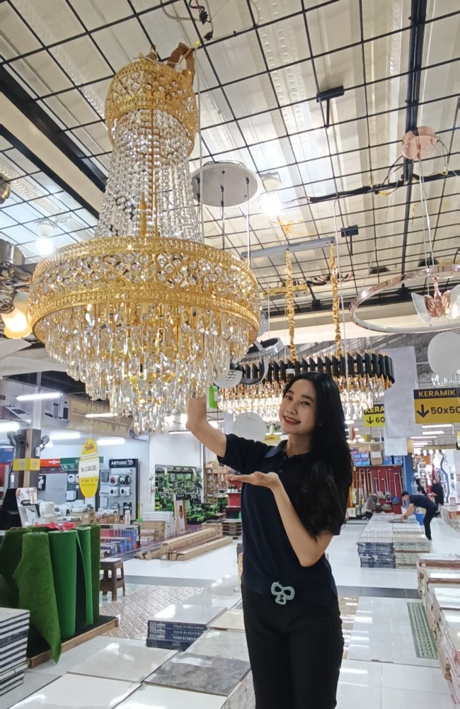 Seorang staf Graha Bangunan Blitar memperlihatkan salah satu koleksi unggulan lampu gantung kristal Fujisan yang memancarkan kemewahan dari setiap sudut. (Foto: Aunur Rofiq/JatimTIMES)
