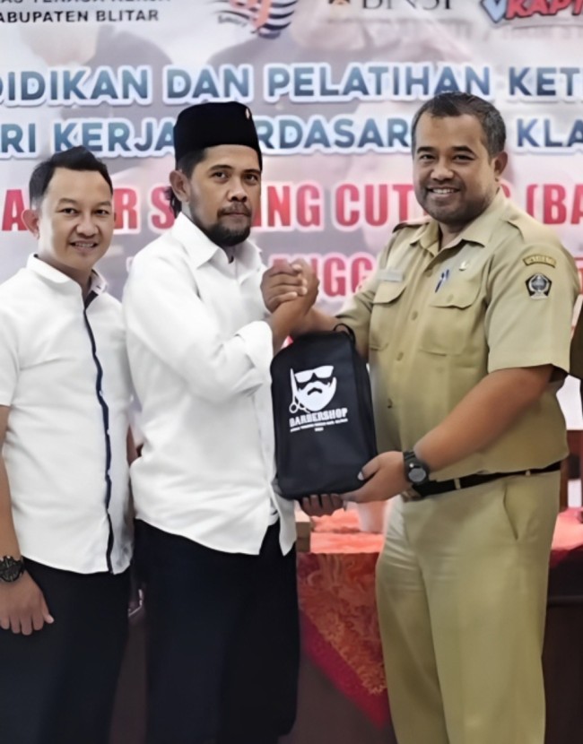 Plt Kepala Disnaker Kabupaten Blitar Nanang Adi Putranto menyerahkan perlengkapan pelatihan barbershop kepada salah satu peserta program Sang Kapten