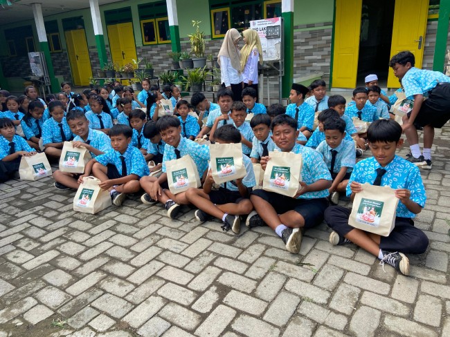Momen para siswa menunjukkan paket gizi yang diterima dari Dinas Peternakan Provinsi Jatim. (Foto: ist)