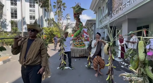 Puluhan warga yang tergabung dalam kelompok DX atau Dinoyo X berjalan di belakang figur babi hutan sambil memikul hasil panen. Mereka juga membawa sebuah gunungan berbentuk naga. (Foto: istimewa)